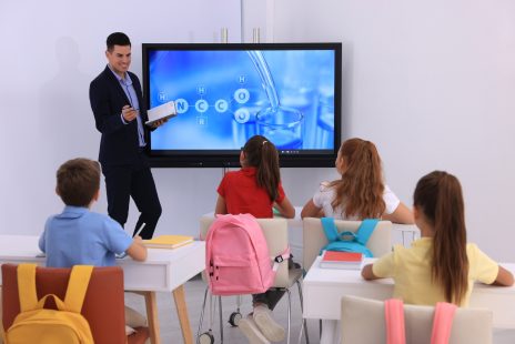 Teacher,Giving,Lesson,To,Pupils,Near,Interactive,Board,In,Classroom